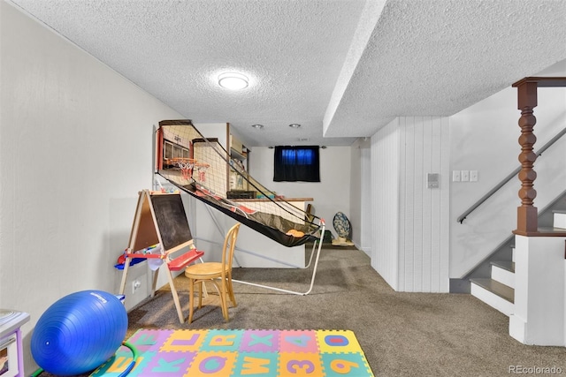 playroom featuring dark colored carpet and a textured ceiling