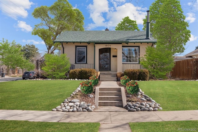 view of front of home featuring fence, a front lawn, and stucco siding