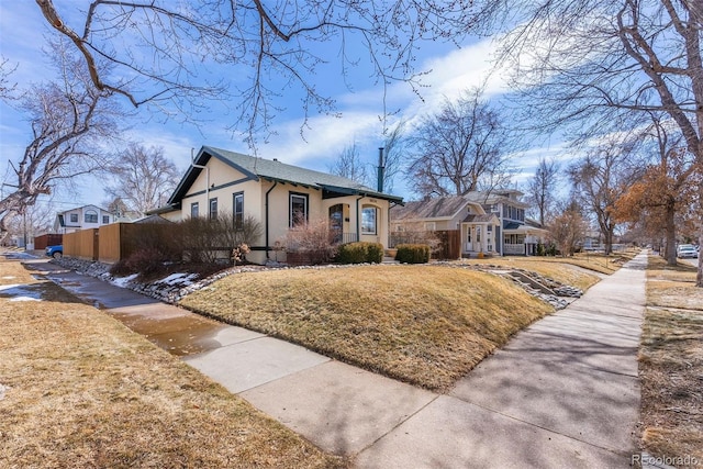 exterior space with fence, a front lawn, and stucco siding