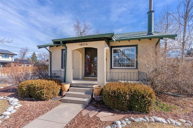 view of exterior entry with a porch and stucco siding