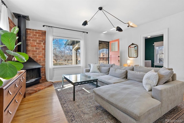 living area featuring light wood-style flooring, a wood stove, and a healthy amount of sunlight