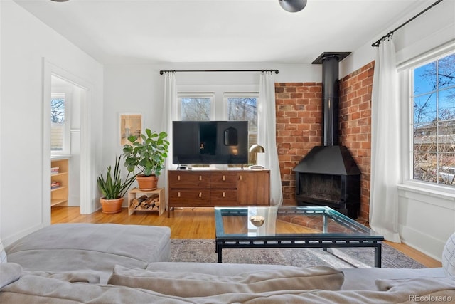 living room featuring a wood stove, light wood-style flooring, and baseboards