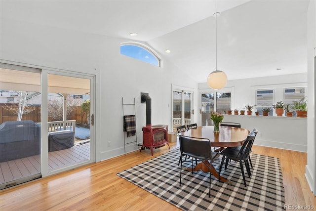 dining space featuring wood finished floors, a wood stove, and a healthy amount of sunlight