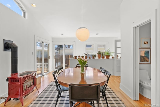 dining space with a wood stove, recessed lighting, light wood-style flooring, and baseboards