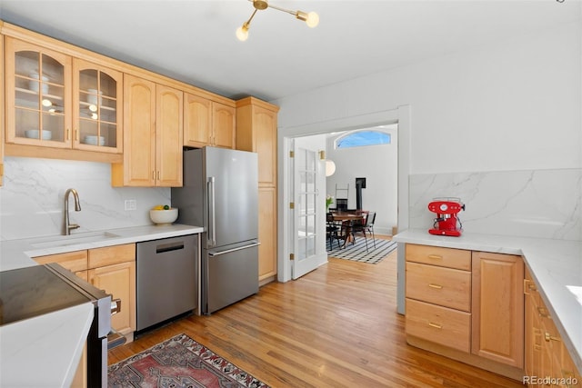 kitchen with appliances with stainless steel finishes, light wood-type flooring, a sink, and light brown cabinetry