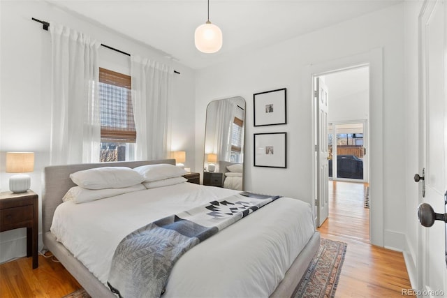 bedroom featuring multiple windows, light wood-type flooring, and baseboards