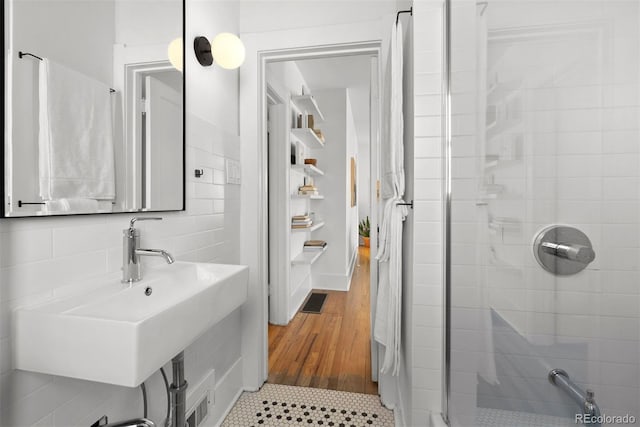 bathroom with a sink, a stall shower, backsplash, and visible vents