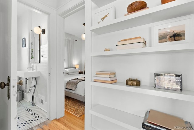 bedroom with light wood-type flooring and a sink