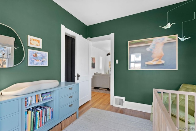 bedroom featuring visible vents, baseboards, and wood finished floors