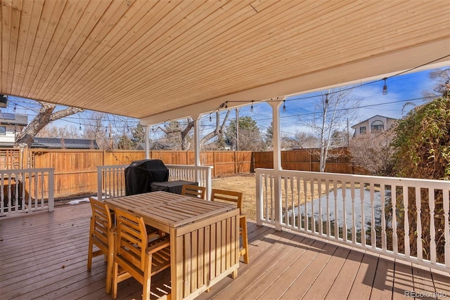 wooden deck with outdoor dining space, a fenced backyard, and grilling area