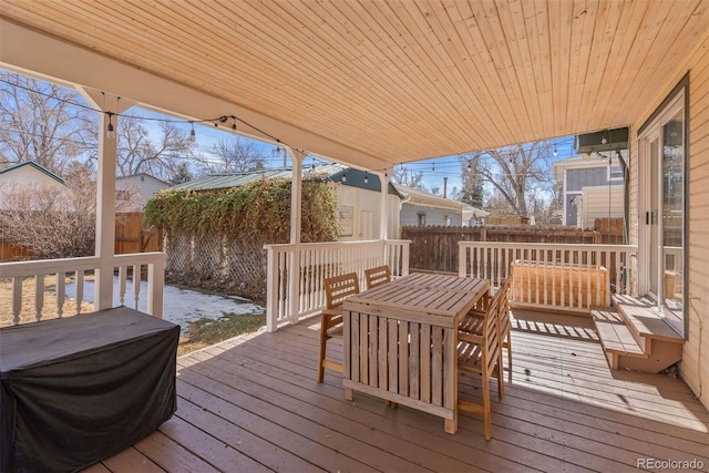 wooden deck featuring an outbuilding, outdoor dining area, a fenced backyard, and a storage shed