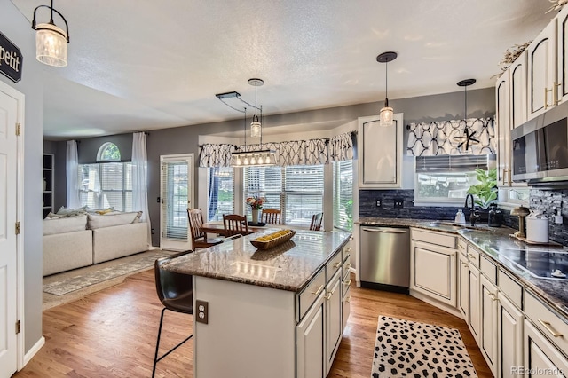 10330 Lions Path, Lone Tree, CO 80124 - kitchen featuring appliances with stainless steel finishes, a sink, a kitchen breakfast bar, decorative backsplash, and light wood finished floors