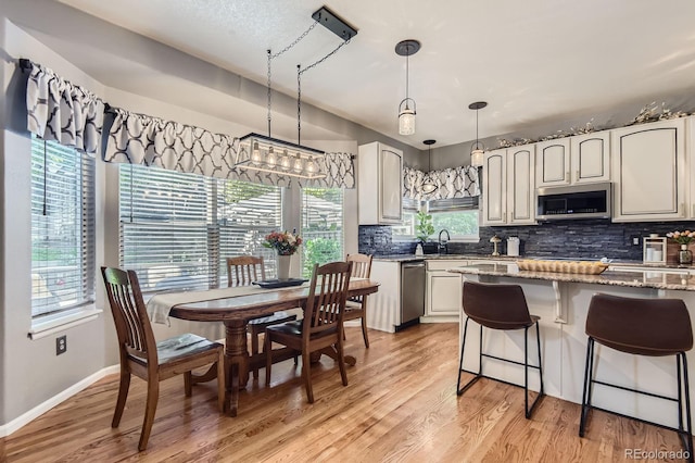 10330 Lions Path, Lone Tree, CO 80124 - kitchen with appliances with stainless steel finishes, tasteful backsplash, light stone countertops, and light wood-type flooring