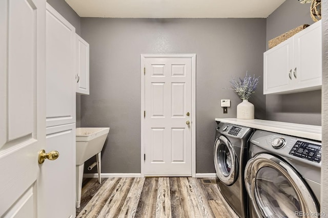 10330 Lions Path, Lone Tree, CO 80124 - laundry room featuring washing machine and dryer, cabinet space, light wood-type flooring, and baseboards