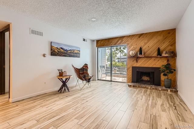7665 E Eastman Ave Unit 111A, Denver, CO 80231 - sitting room with a textured ceiling, wood walls, light wood-style floors, a fireplace with raised hearth, and baseboards