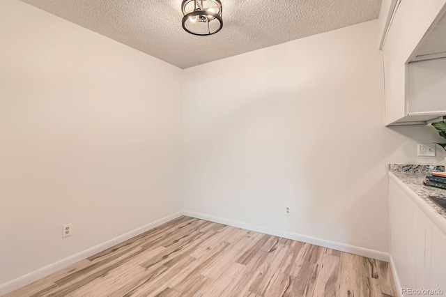 7665 E Eastman Ave Unit 111A, Denver, CO 80231 - unfurnished dining area featuring light wood-style flooring, a textured ceiling, and baseboards