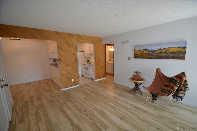 7665 E Eastman Ave Unit 111A, Denver, CO 80231 - living area featuring wood walls, light wood-style floors, baseboards, and a textured ceiling
