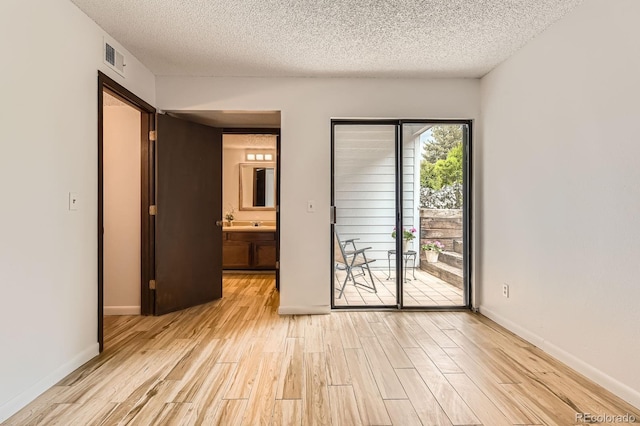 7665 E Eastman Ave Unit 111A, Denver, CO 80231 - spare room featuring light wood finished floors, a textured ceiling, and baseboards