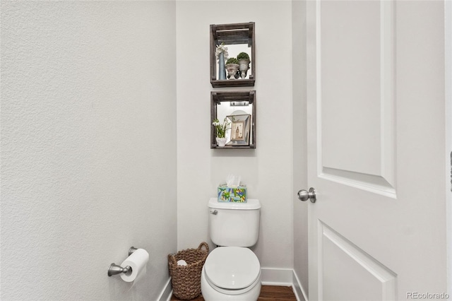 bathroom featuring toilet, baseboards, and wood finished floors