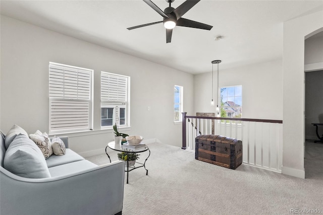 carpeted living area featuring baseboards, ceiling fan, and arched walkways