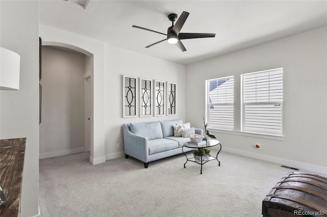 living room with visible vents, ceiling fan, carpet floors, arched walkways, and baseboards