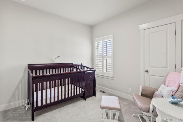 carpeted bedroom featuring baseboards, a nursery area, and visible vents
