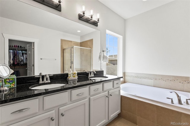 bathroom featuring a sink, double vanity, a stall shower, and a bath