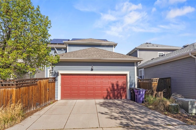 garage with concrete driveway and fence