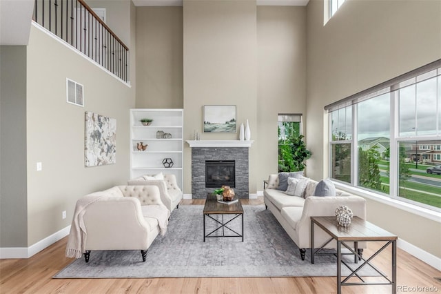 676 Fossil Bed Cir, Erie, CO 80516 - living room featuring a high ceiling, baseboards, wood finished floors, and a stone fireplace