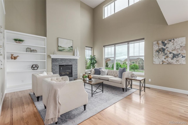 676 Fossil Bed Cir, Erie, CO 80516 - living room featuring wood finished floors, a towering ceiling, a fireplace, and baseboards