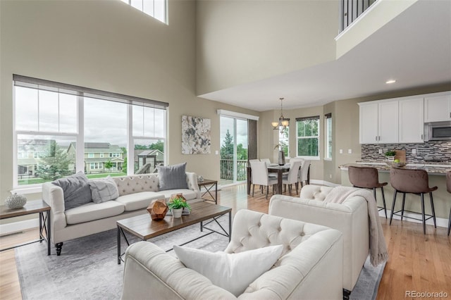 676 Fossil Bed Cir, Erie, CO 80516 - living area featuring a towering ceiling, light wood-style floors, a chandelier, baseboards, and recessed lighting