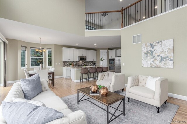 676 Fossil Bed Cir, Erie, CO 80516 - living area featuring a chandelier, light wood finished floors, a high ceiling, baseboards, and recessed lighting