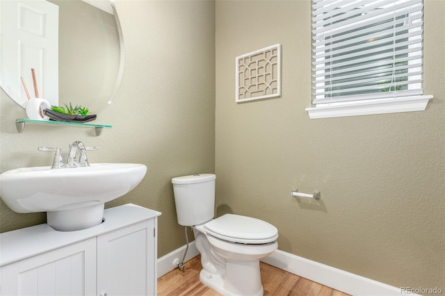 676 Fossil Bed Cir, Erie, CO 80516 - half bathroom with wood finished floors, toilet, baseboards, and a sink