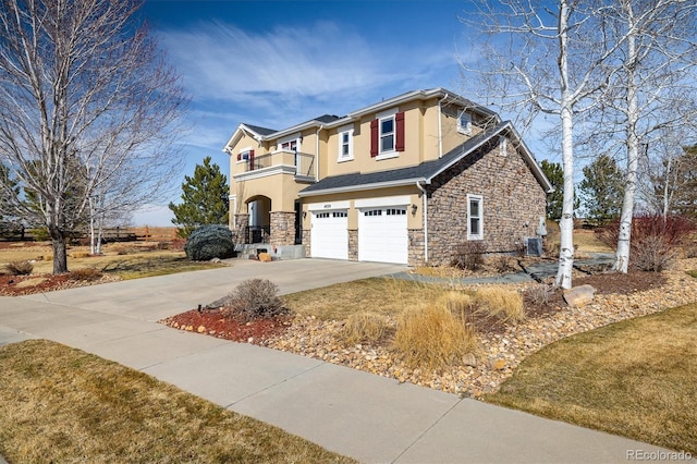 view of front of house featuring stucco siding, a balcony, a garage, stone siding, and driveway