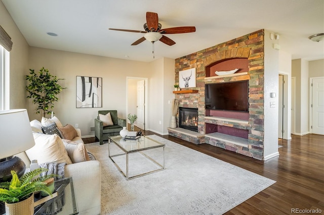 living area with ceiling fan, a fireplace, baseboards, and wood finished floors