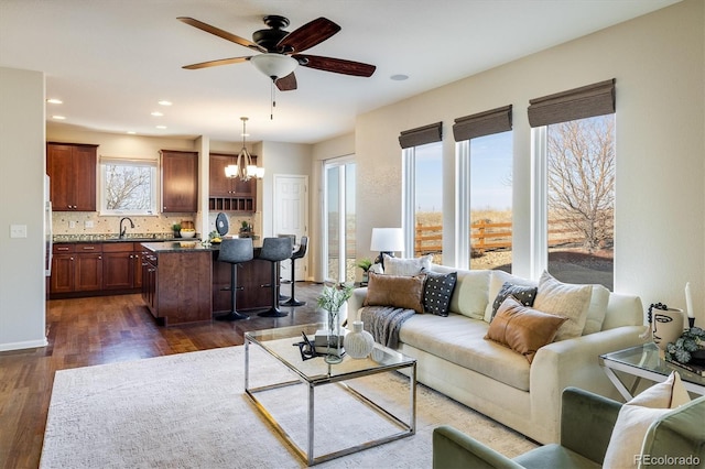 living area with dark wood-style floors, recessed lighting, and ceiling fan with notable chandelier