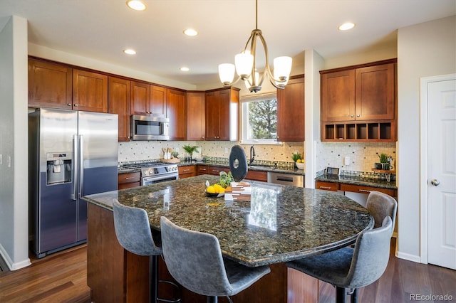 kitchen featuring dark wood-style floors, appliances with stainless steel finishes, a sink, and a center island