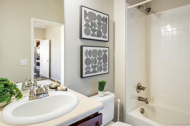 full bath featuring a textured wall, tub / shower combination, vanity, and toilet