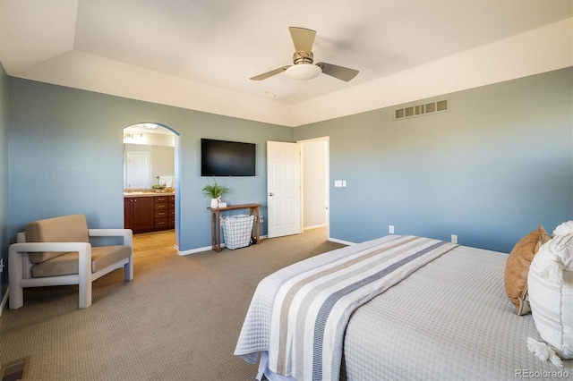 bedroom with light colored carpet, arched walkways, visible vents, and baseboards