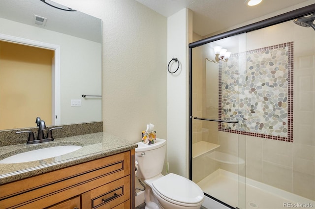 bathroom with toilet, a stall shower, vanity, and visible vents