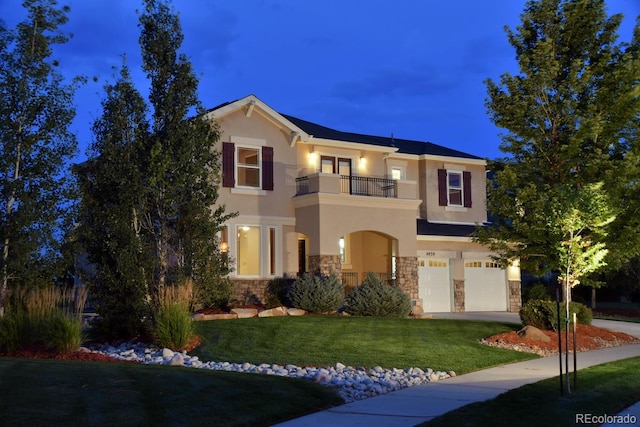 mediterranean / spanish house with a balcony, a garage, stone siding, stucco siding, and a front yard