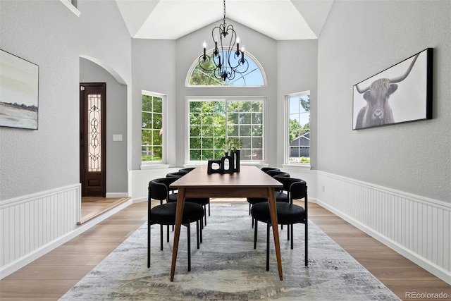 1473 E 130th Dr, Thornton, CO 80241 - dining space with wood finished floors, a chandelier, a textured wall, arched walkways, and lofted ceiling