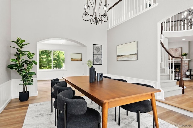 1473 E 130th Dr, Thornton, CO 80241 - dining room featuring a chandelier, light wood-style floors, arched walkways, a towering ceiling, and stairs