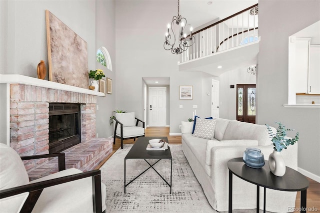 1473 E 130th Dr, Thornton, CO 80241 - living room featuring wood finished floors, a brick fireplace, a towering ceiling, and a chandelier