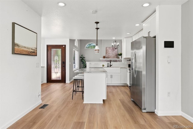 1473 E 130th Dr, Thornton, CO 80241 - kitchen featuring stainless steel refrigerator with ice dispenser, a kitchen bar, white cabinets, light wood finished floors, and recessed lighting