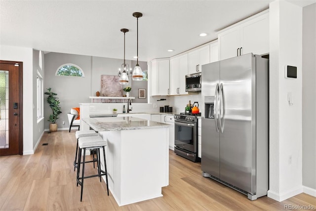 1473 E 130th Dr, Thornton, CO 80241 - kitchen featuring stainless steel appliances, light wood finished floors, white cabinetry, pendant lighting, and light stone countertops