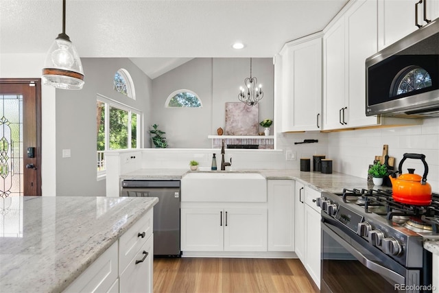 1473 E 130th Dr, Thornton, CO 80241 - kitchen with stainless steel appliances, a chandelier, light wood-style flooring, white cabinetry, and vaulted ceiling