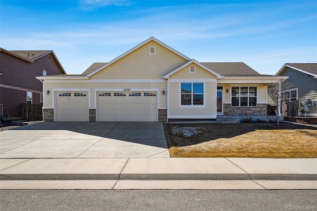 craftsman-style home with stone siding, an attached garage, fence, and driveway