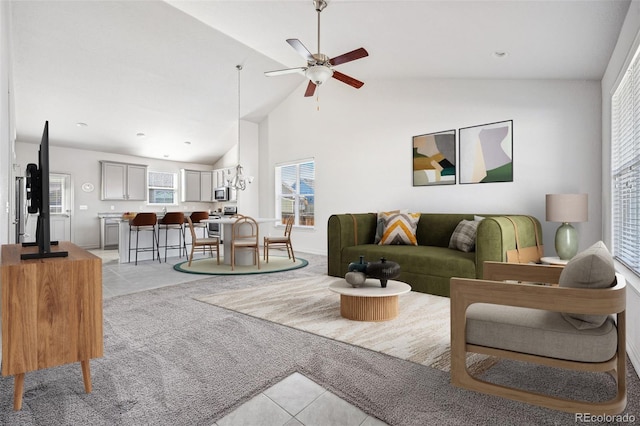 living area featuring high vaulted ceiling, light colored carpet, light tile patterned flooring, and ceiling fan