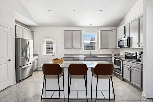 kitchen with lofted ceiling, appliances with stainless steel finishes, and gray cabinets